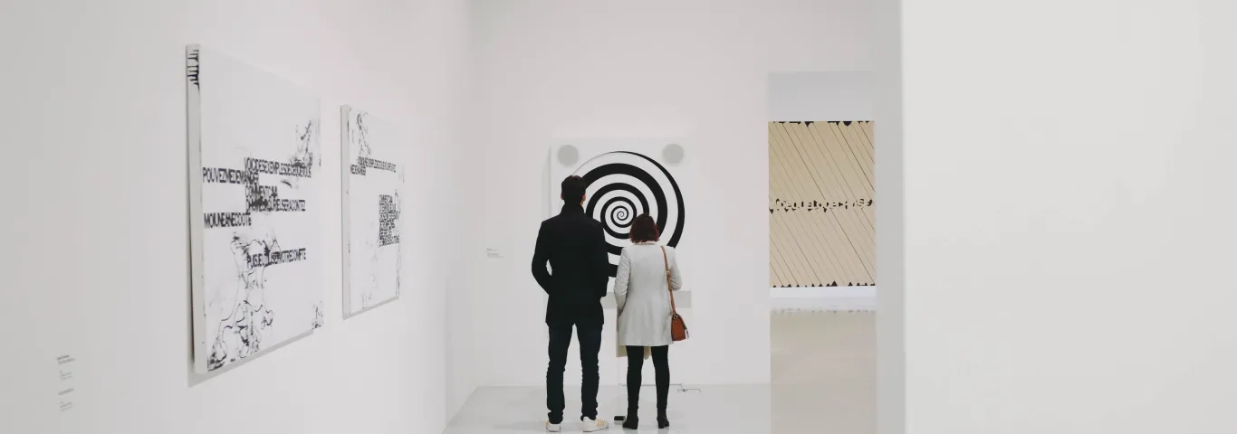 Two people standing in an art gallery, viewing a painting